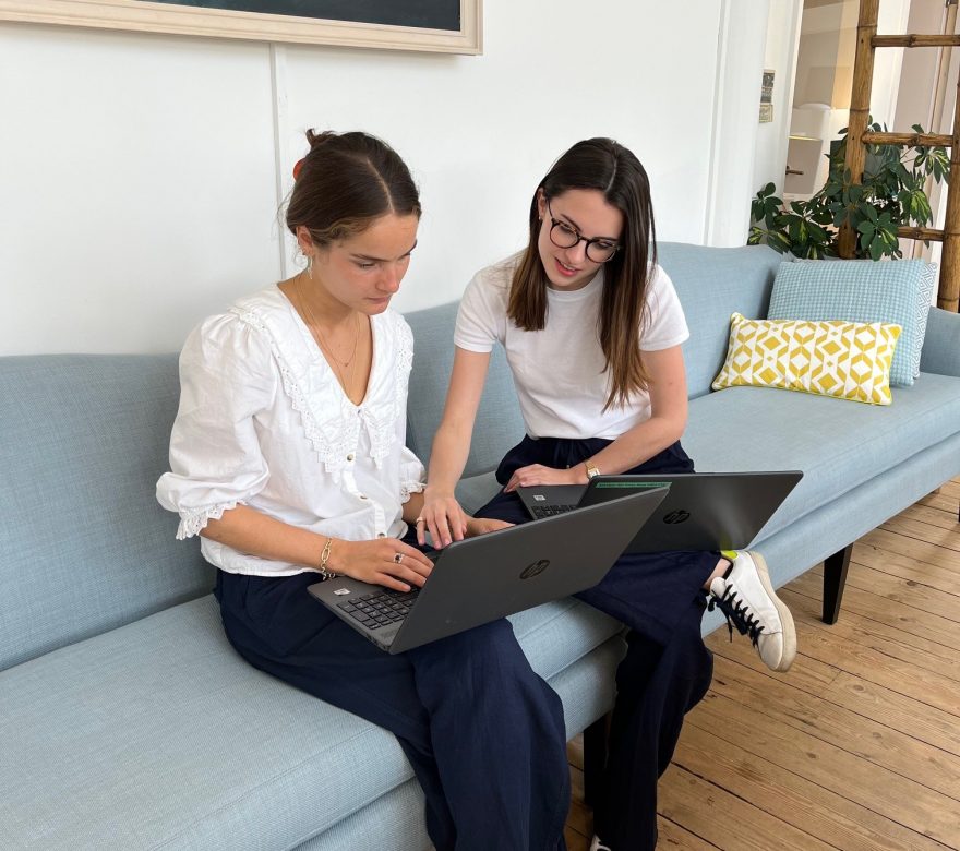 two girls sitting on a sofa with a laptop