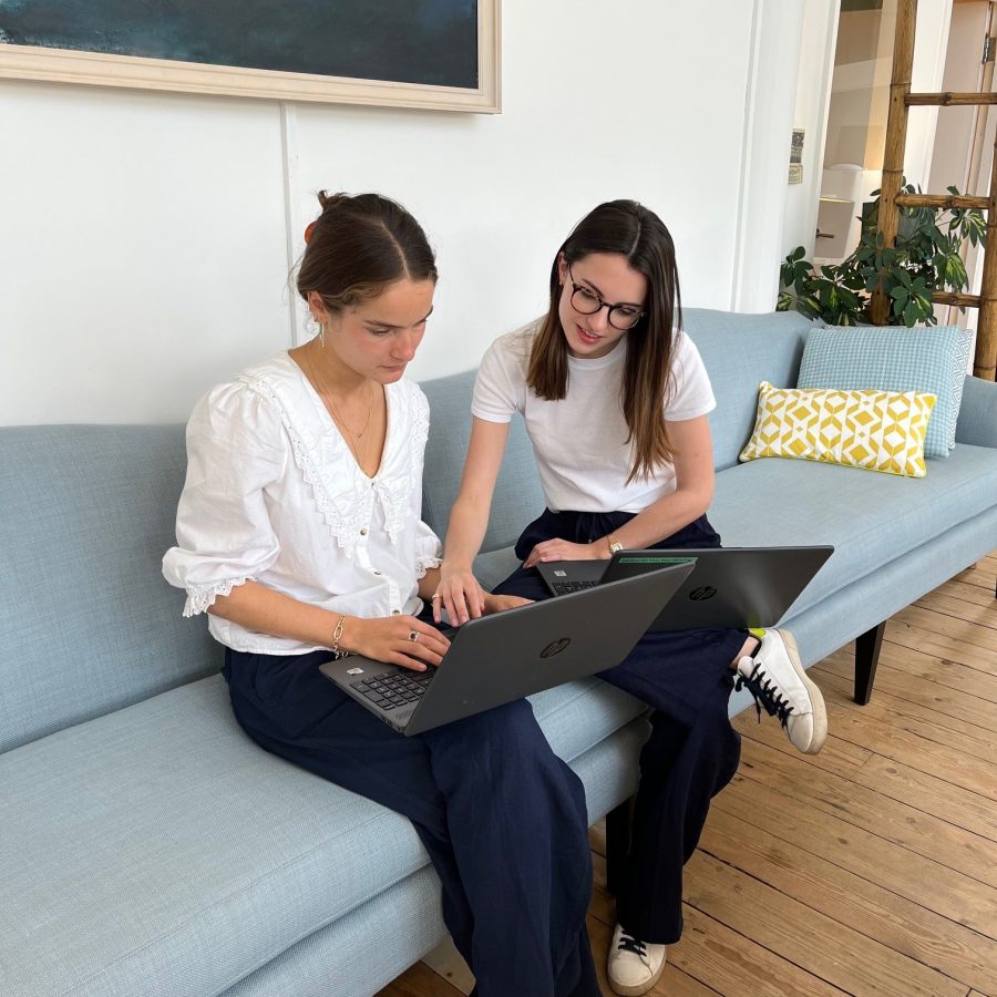 two girls sitting on a sofa with a laptop